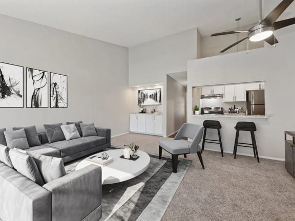 Model Living Room with Carpet and View of Kitchen at Verona Park Apartments located in Mesa, AZ-LRGAM.