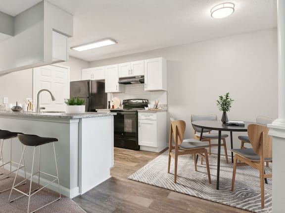 Model Kitchen with Wood-Style Flooring, White Cabinets and View of Living Room at Park 2300 Apartments in Charlotte, NC-LRGAM.