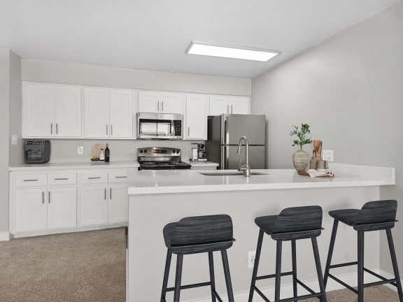 Model Kitchen with White Cabinets and Wood-Style Flooring at Crystal Creek Apartments in Phoenix, AZ-LRGAM.