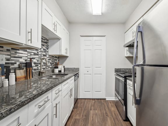 Model Kitchen with White Cabinets and Wood-Style Flooring at Lakeside Retreat Apartments located in Peachtree Corners, GA-LRGAM.
