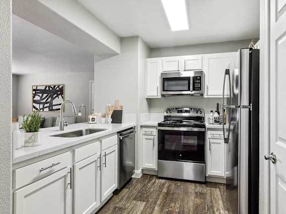 East Las Vegas, NV, Apartments Near Walmart - Monterra - Modern Kitchen With White Cabinets, Quartz-Look Counters, Stainless Steel Refrigerator, Microwave, And Gas Range.