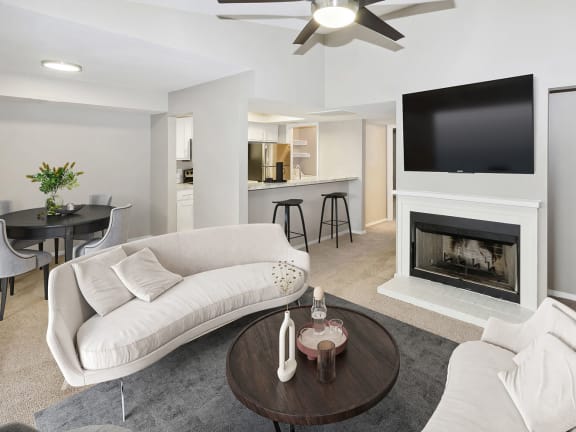 Model Living Room with Carpet, Fireplace & View of Kitchen at Woodcreek Apartments located in Arlington, TX-LRGAM.