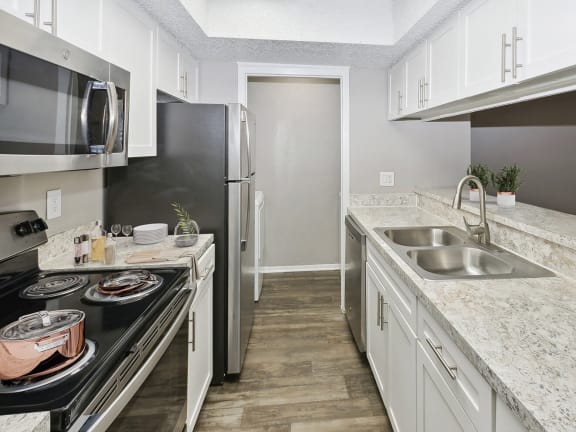 Model Kitchen with White Cabinets and Wood-Style Flooring at Woodcreek Apartments located in Arlington, TX-LRGAM.