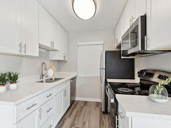 Model Kitchen with White Cabinets and Wood-Style Flooring at Bridges on Sunset Apartments in Suisun City, CA.