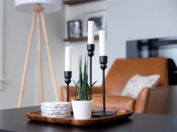 a close up of a table with a wooden tray with three black candlesticks on it