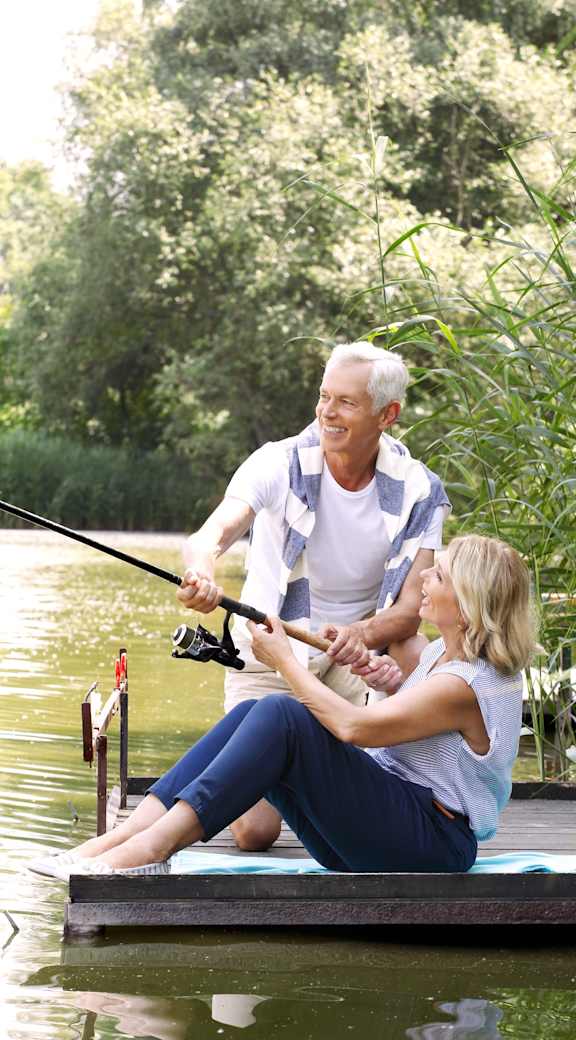 A man and a woman are fishing on a dock.