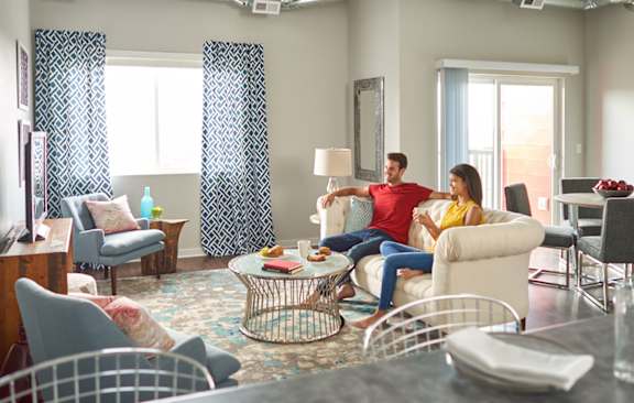 a man and woman sitting on a couch in a living room at Vue Apartments, Iowa, 50309