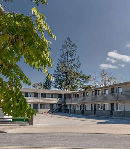 A building with the sign "Walloon Manor" is surrounded by trees and a clear sky.