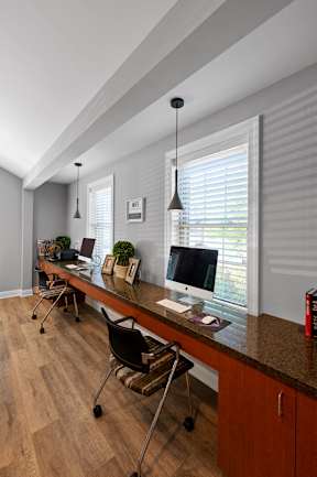 A resident business center with two computer stations, a long desk, and two windows in Severgn Apartments clubhouse.