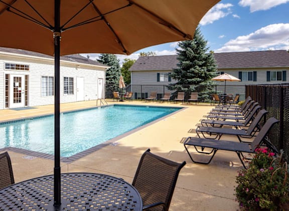 A poolside area with chairs and an umbrella.