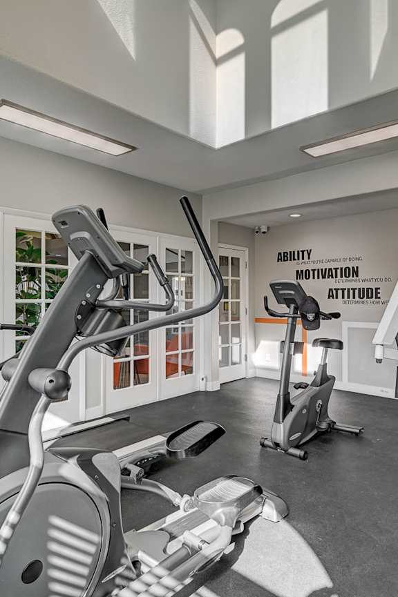 A gym with a row of exercise bikes and a sign that says "Ability Motivation Attitude".