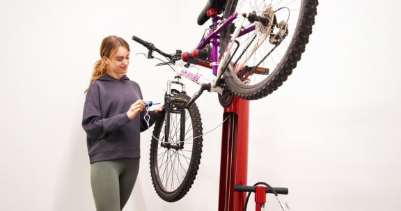 a woman is fixing a bike on a pole at Southpark on Whyte, Edmonton, Alberta, T6E 3S3