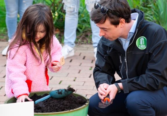 a man and a young girl planting seeds in a pot of soil