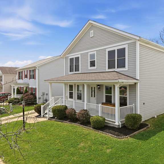 A house with a grey siding and a white porch.