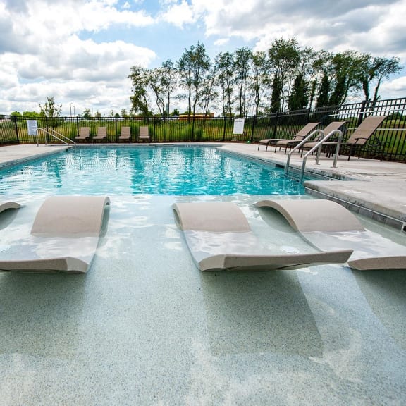 a swimming pool with lounge chairs next to a resort style pool