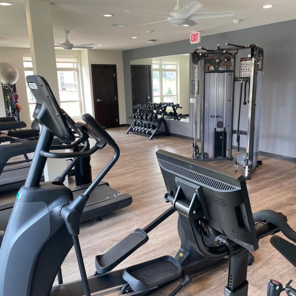 a gym with cardio equipment and weights on a wooden floor