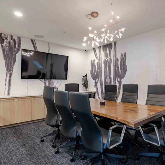 A conference room with a cactus mural on the wall and a flat screen TV.
