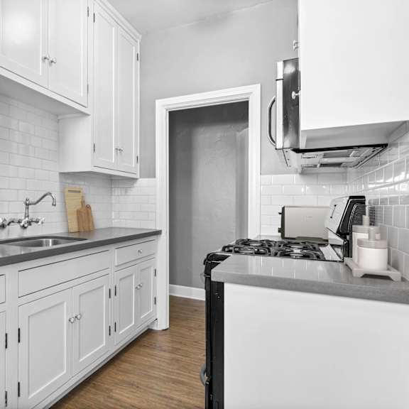 A kitchen with white cabinets and a black stove top.