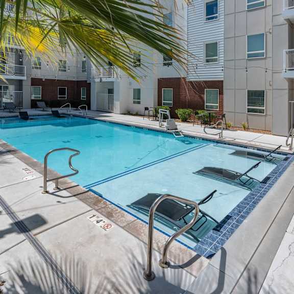 A swimming pool surrounded by a metal railing and a building in the background. 605 Place Student Housing & Co-Living, St George