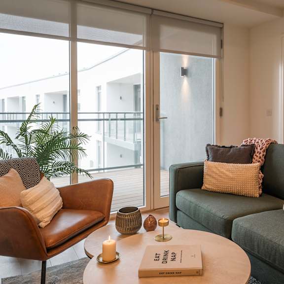 A living room with a green couch and a brown armchair at Cherrywood Apartments, D18 VY3V, DUBLIN 18