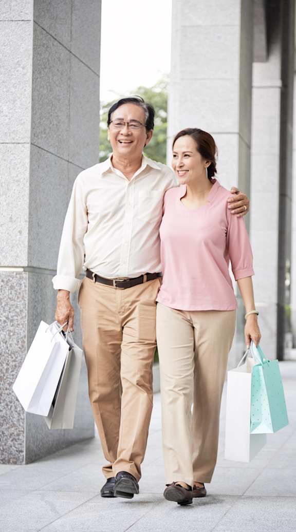 A man and a woman are walking down the street carrying shopping bags.