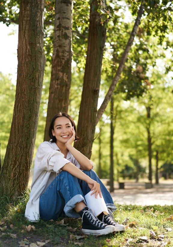a woman sitting in the grass in a park