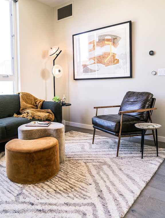 A living room with a black leather chair and a brown ottoman.