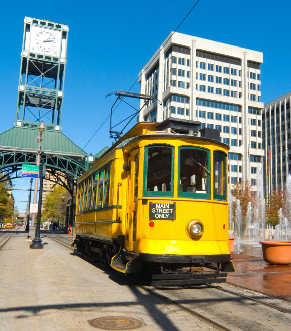 a yellow streetcar on the tracks in front of a clock tower