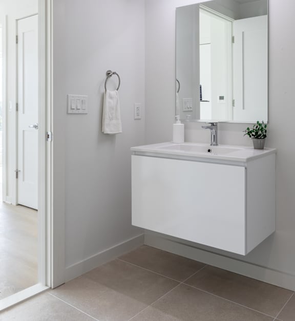 A white bathroom sink with a mirror and a light above it.