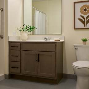 A bathroom with a toilet, sink, and mirror.