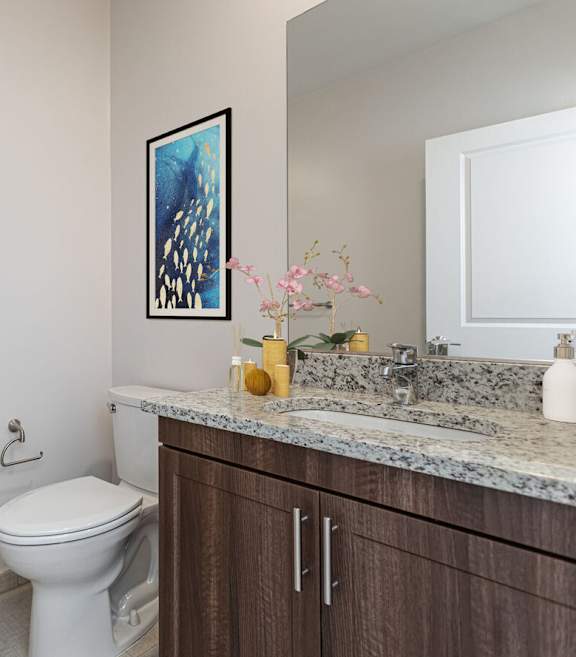 A bathroom with a toilet, sink, and a painting on the wall.