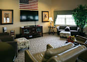 Thumbnail 1 of 11 - A living room with a large leather chair and a television.