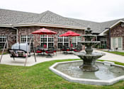 Thumbnail 4 of 11 - A patio with a table and chairs and a fountain.