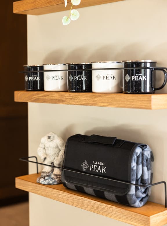 a shelf with a tote bag and cups on it and two shelves on top