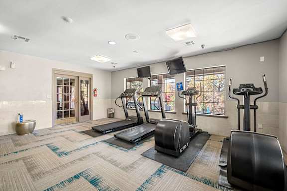 A gym with treadmills, elliptical machines, and a weight machine.