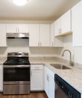 A kitchen with a stainless steel refrigerator and white cabinets. at South Winds Apartments, Fall River, 02720