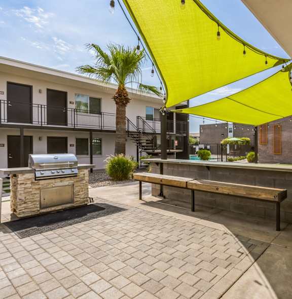 a patio with a grill and tables under a blue umbrella