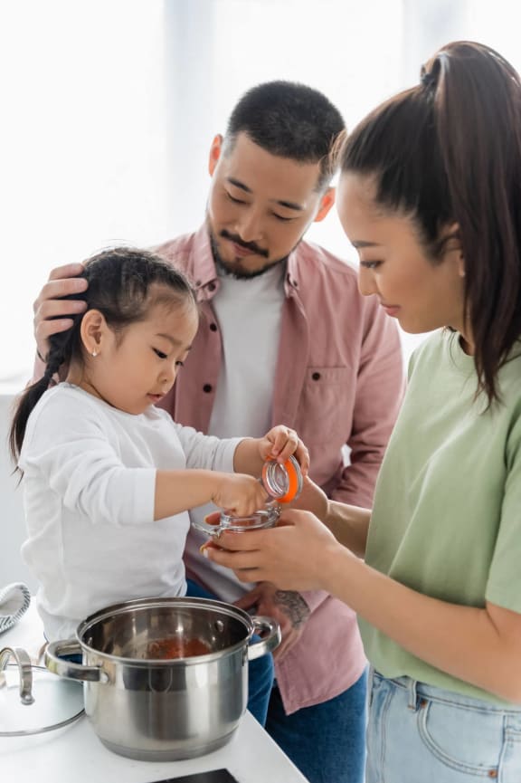 a little girl cooking with her family in the kitchen