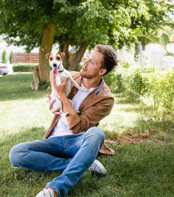 a man sitting on the grass holding a dog