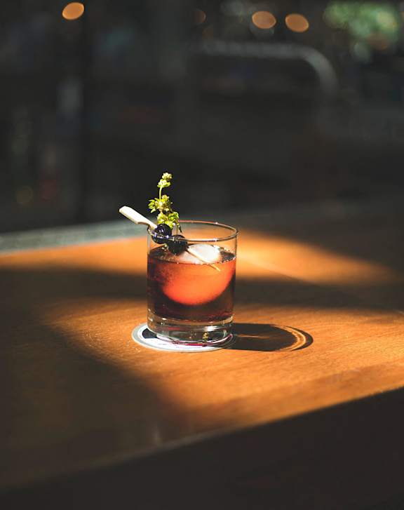 A glass of a cocktail with a garnish on a wooden surface.