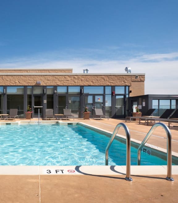 a swimming pool with lounge chairs and a building in the background