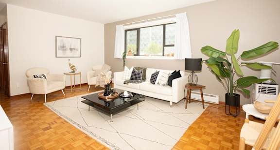 A living room with a white couch, a coffee table, and a large window.