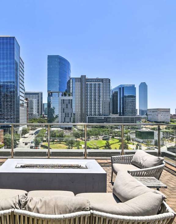 A rooftop patio with a table and chairs overlooking a city skyline.