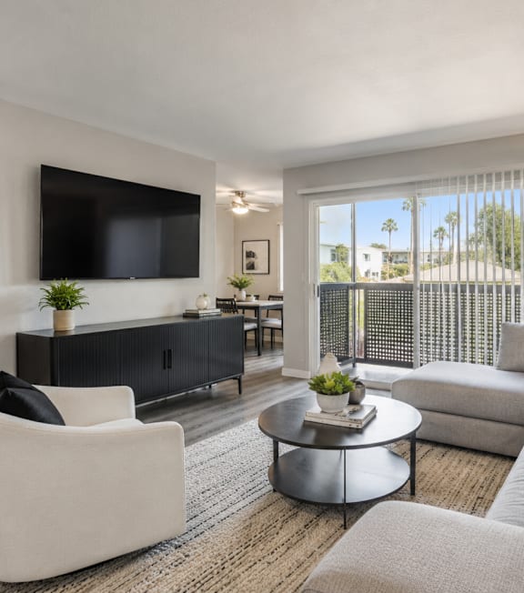 A modern living room with a grey sofa, a white armchair, and a black and white patterned cushion.