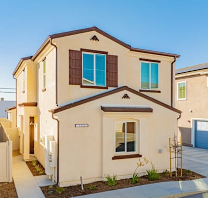 A beige house with a brown roof and a blue garage door.