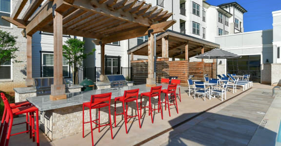 a patio with red chairs and a table with chairs at The Eddy at Riverview, Smyrna, 30126