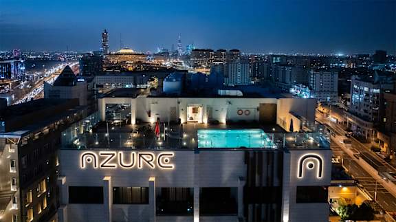 Azure hotel with a pool in the middle of the city at night.