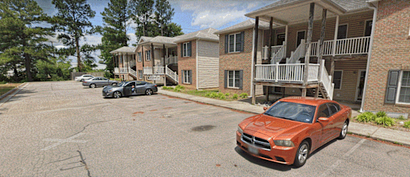 a row of apartment buildings with cars parked in front of them