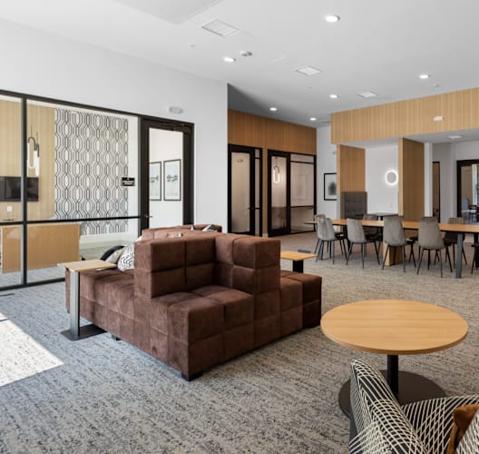 A modern living room with a brown sofa, a wooden table, and a grey carpet.