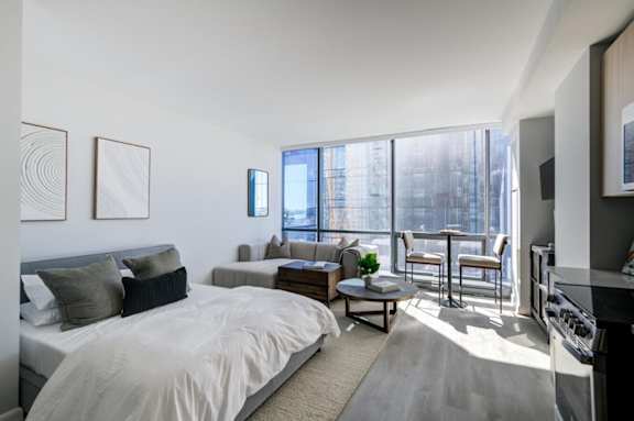 A bedroom with a large bed and a balcony with a table and chairs.